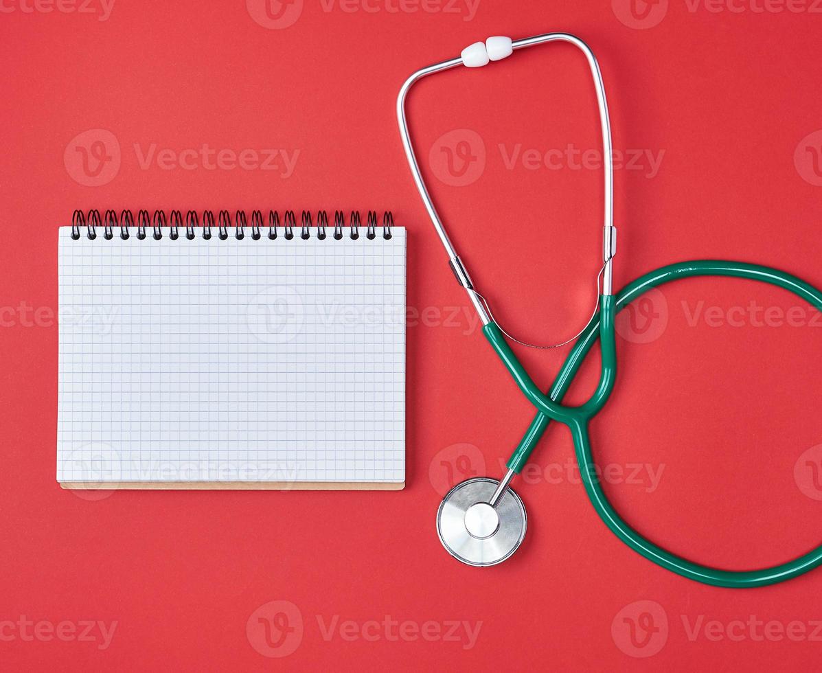 libreta en blanco abierta y estetoscopio médico verde foto