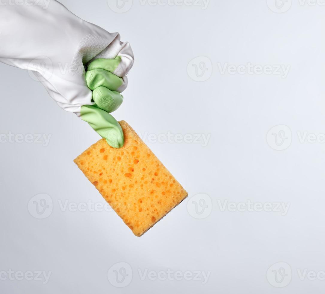 gloved hand holds yellow kitchen sponge photo