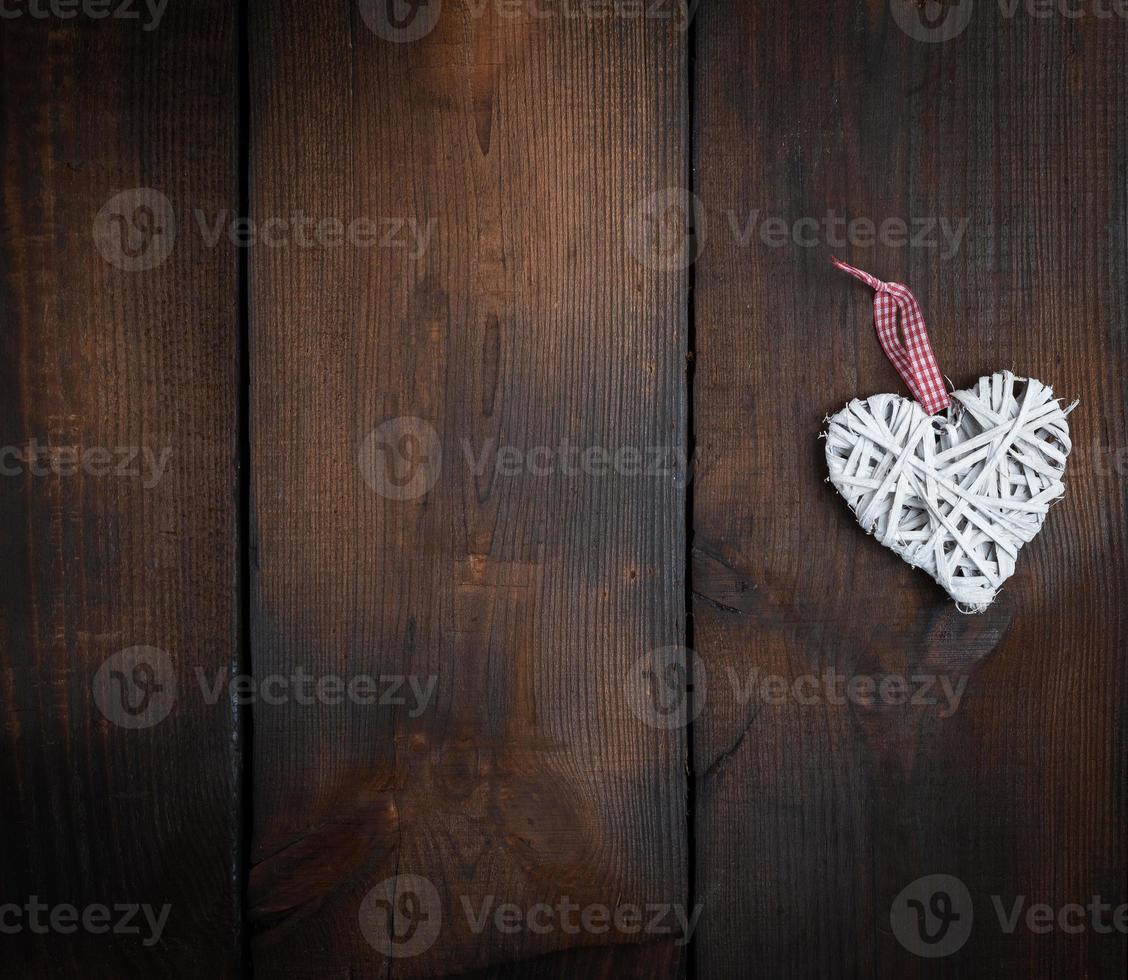 corazón de mimbre blanco sobre un fondo de tablón de madera marrón foto