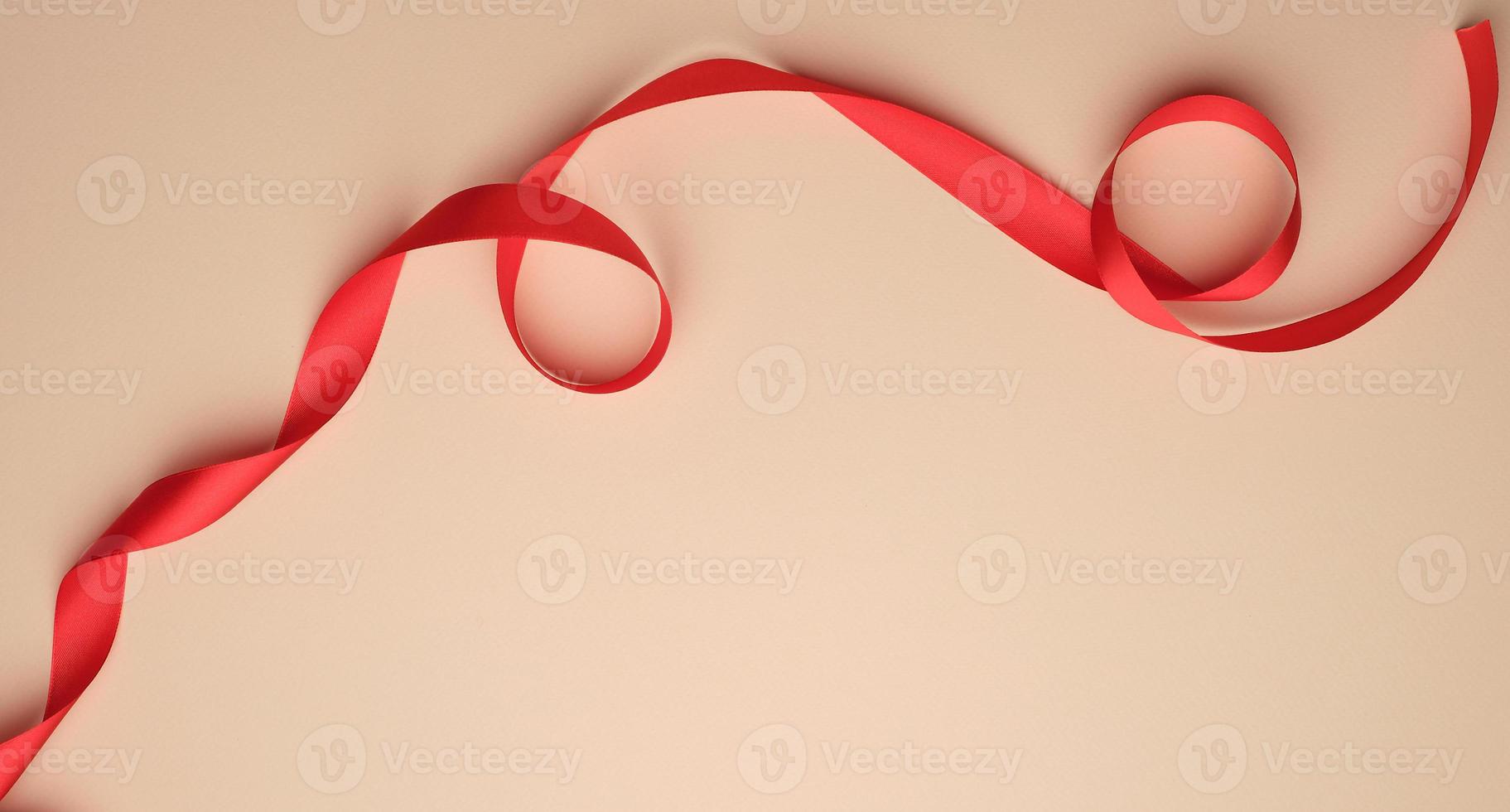 red silk ribbon twisted on a beige background, festive backdrop photo
