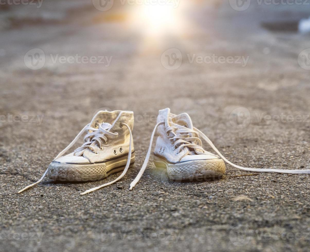 pair of very old white sneakers with untied laces photo