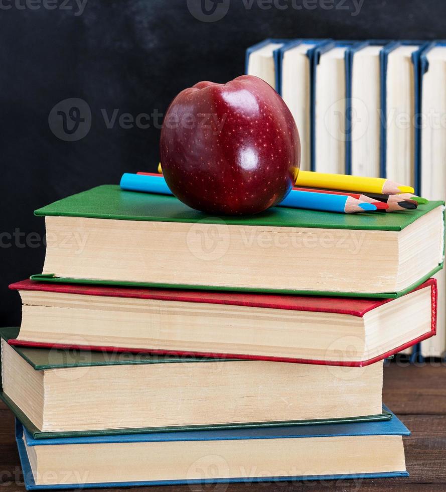 ripe red apple lying on a stack of books photo