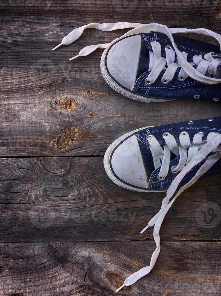 Old worn blue sneakers with white laces untied photo