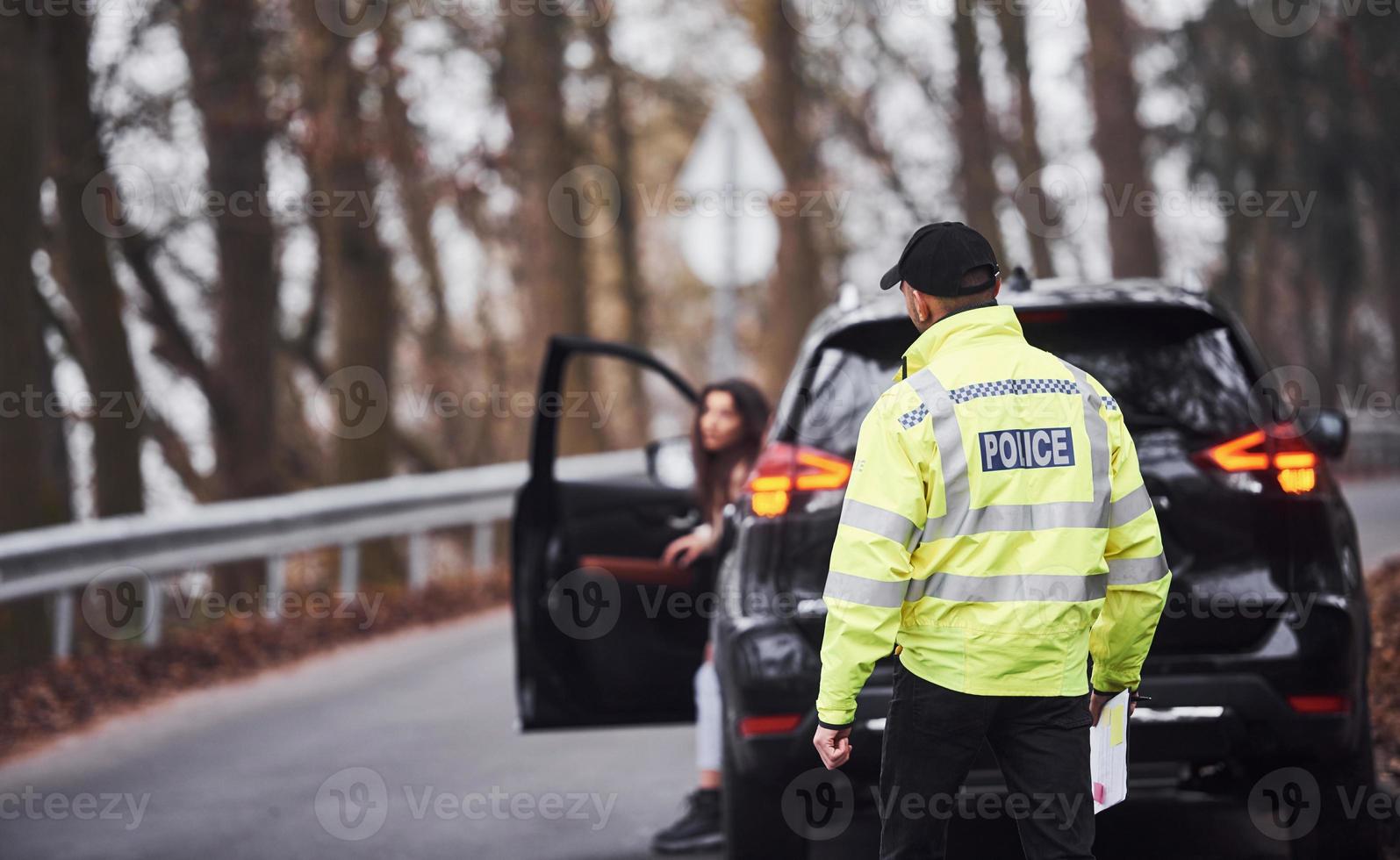 Male police officer in green uniform walking to the vehicle on the road photo