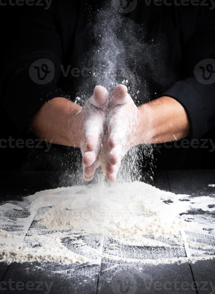 man's hands and splash of white wheat flour photo