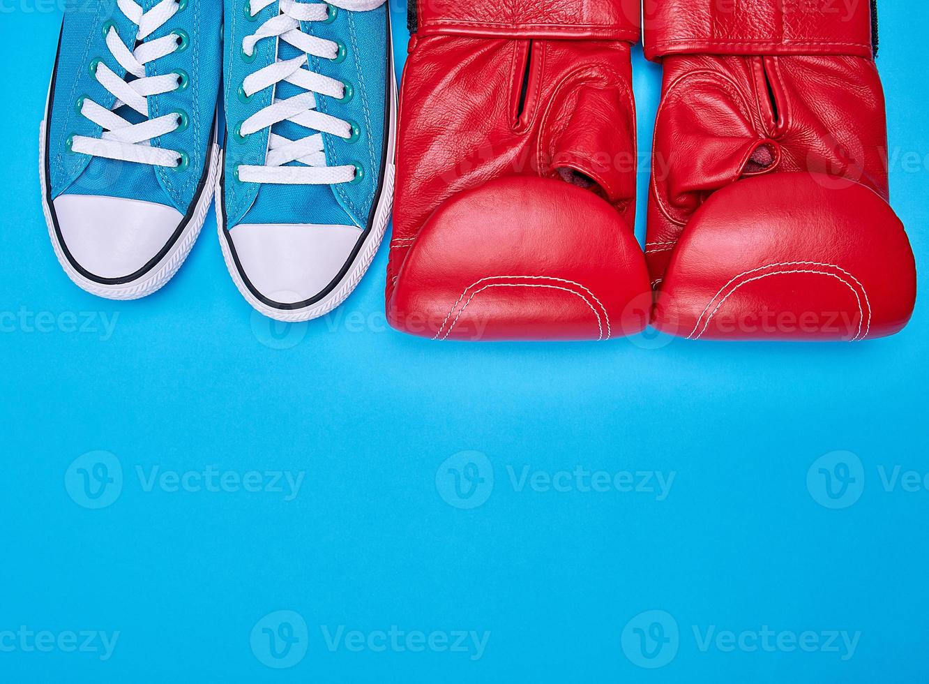 pair of red boxing gloves and blue textile sneakers photo