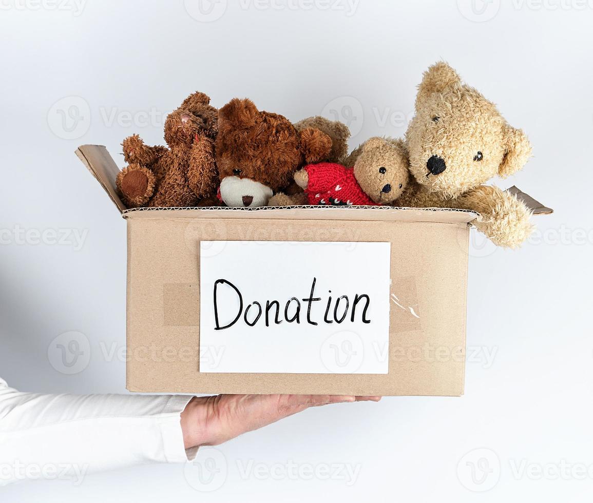 male hand holding a paper brown box with children's toys photo