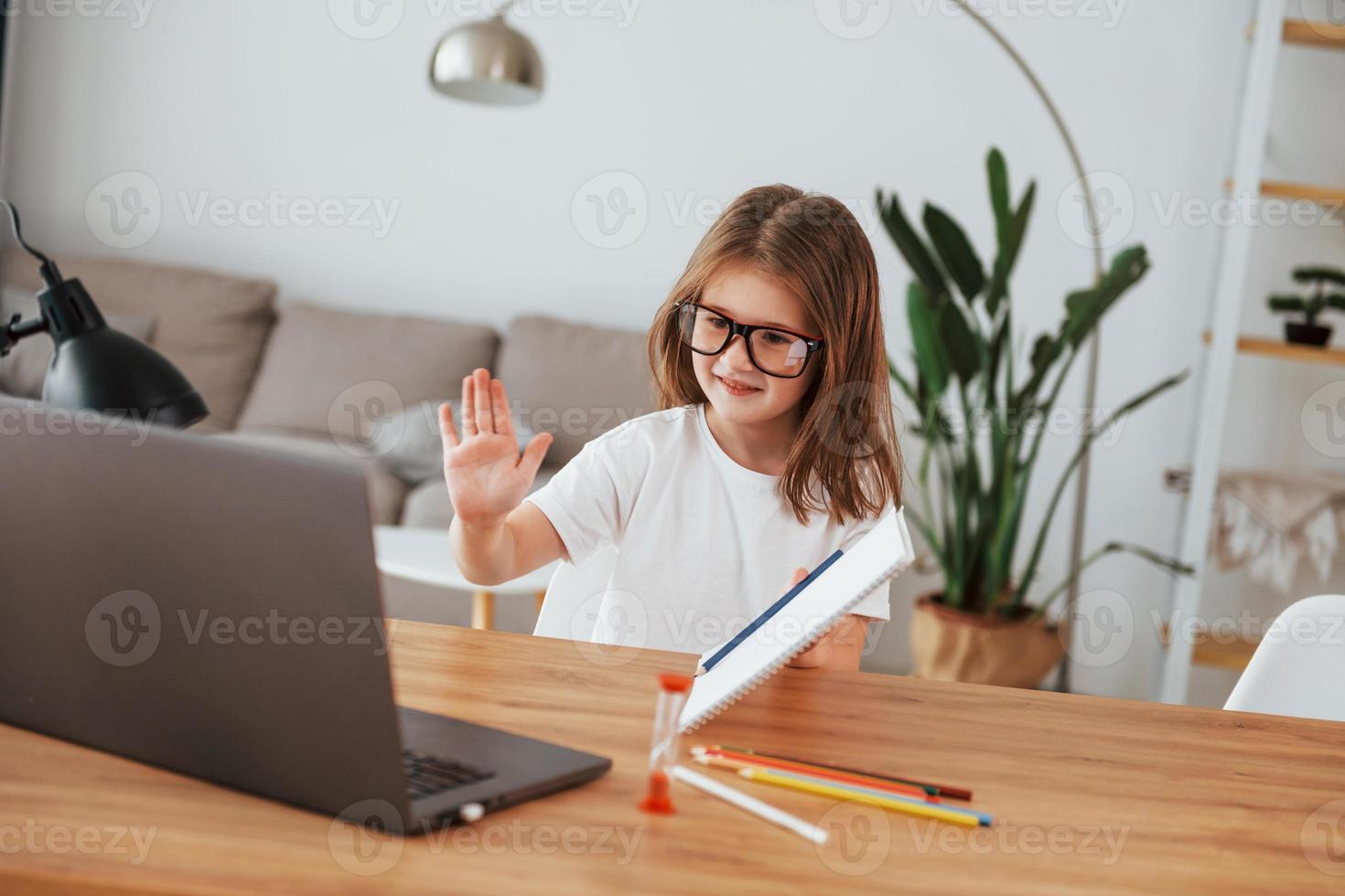 la niña está sentada junto a la mesa y está aprendiendo a dibujar foto