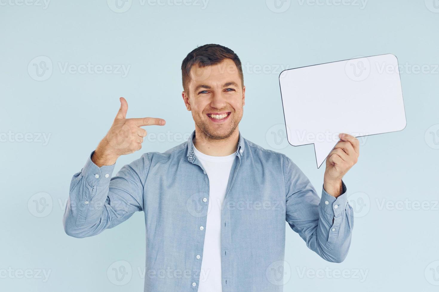 Smiling and having good mood. Man standing in the studio with empty signs for the text photo