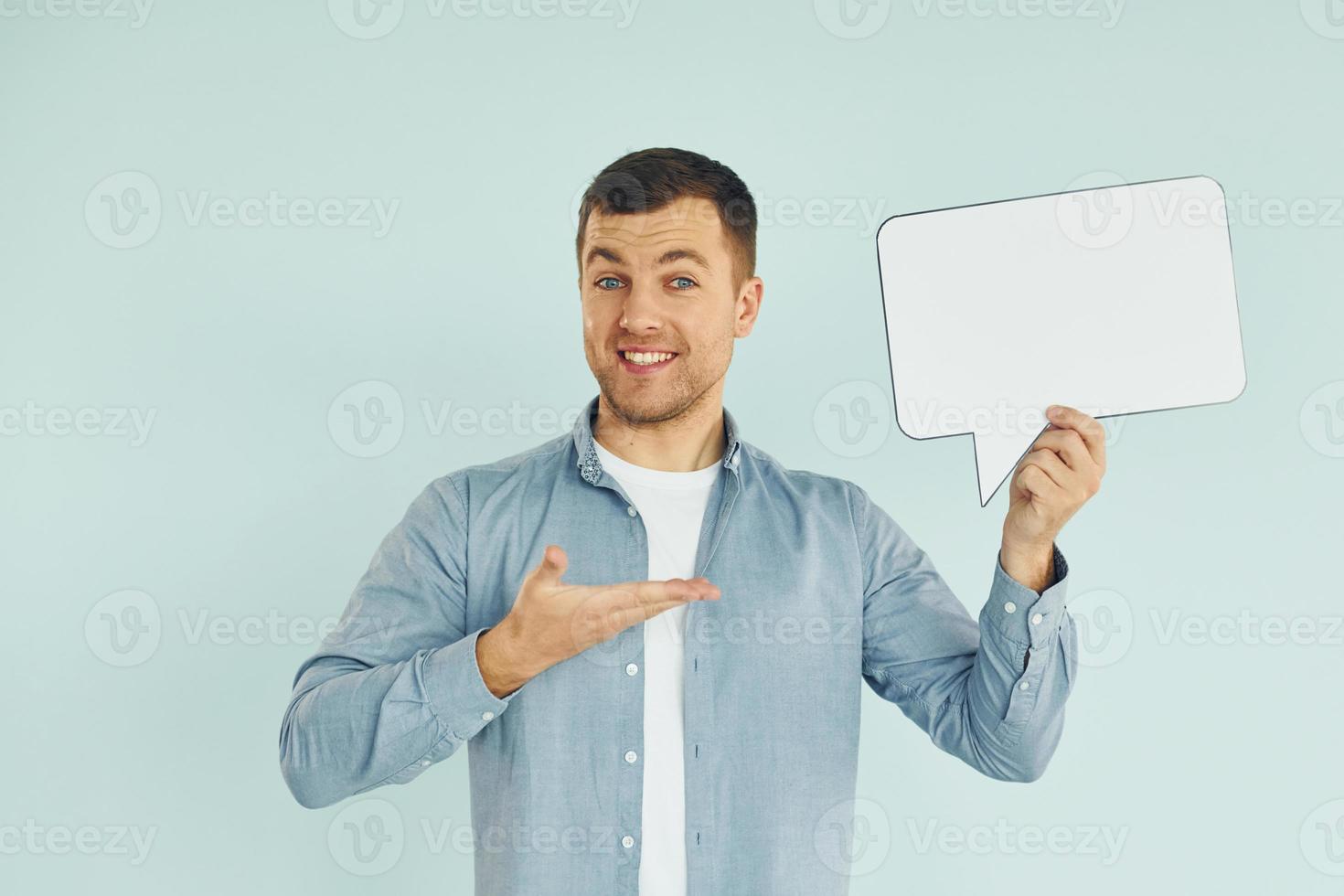 Smiling and having good mood. Man standing in the studio with empty signs for the text photo