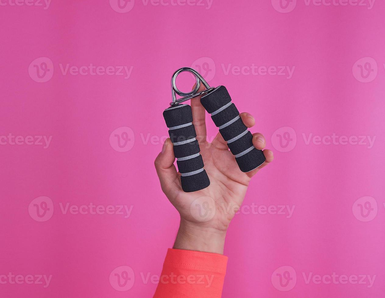 black espander in female hand on pink background photo