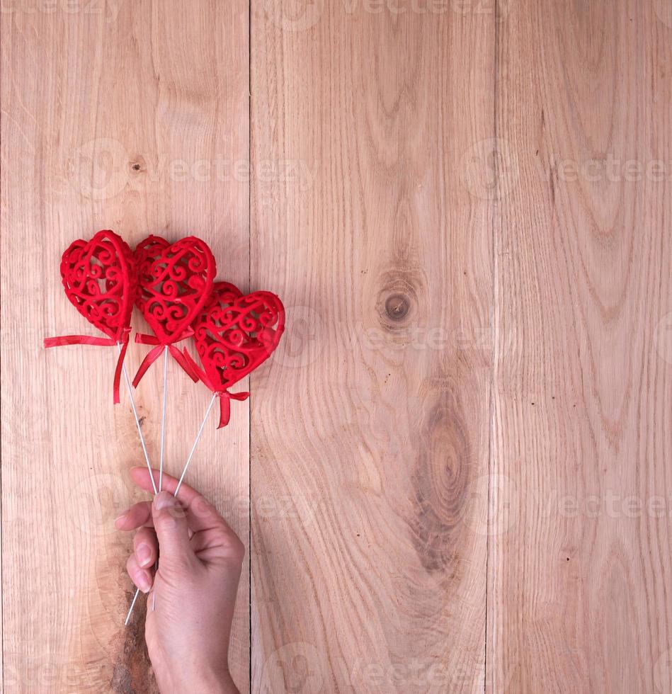 red hearts in human hand on yellow wooden background photo