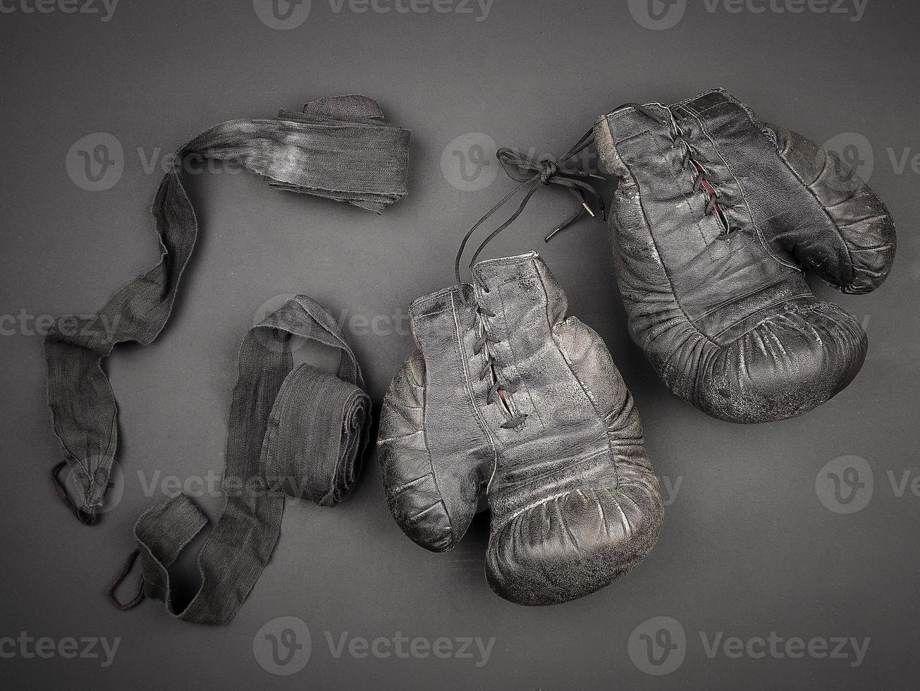 very old vintage leather black boxing gloves with laces and a black elastic bandage for rewinding photo