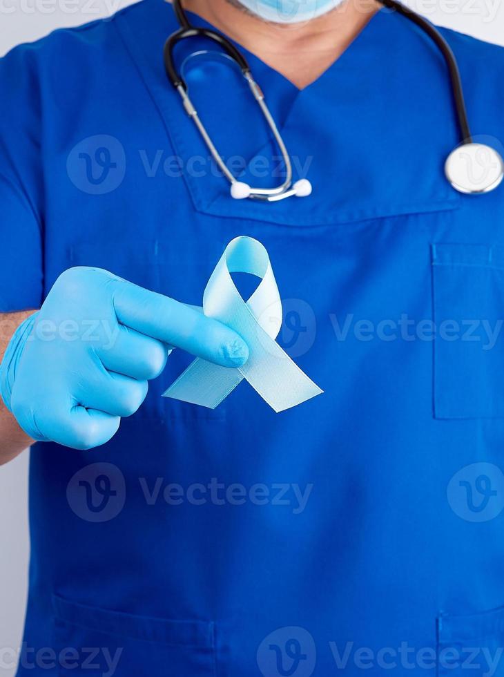 doctor in uniform and latex gloves holding a blue ribbon in his hand photo