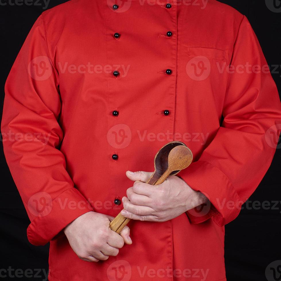 chef in red uniform holding old wooden spoons photo