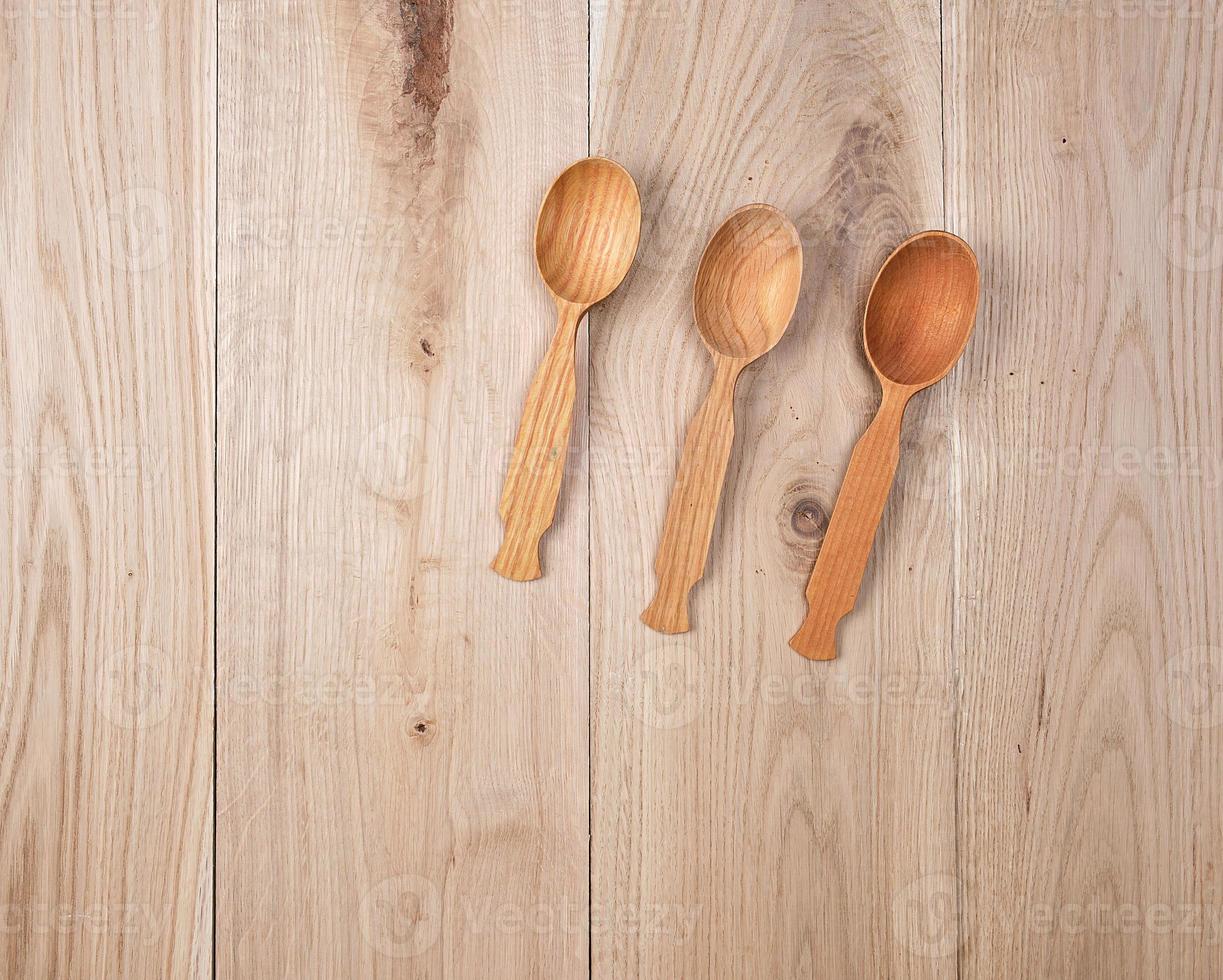 three empty wooden spoons on a background of oak boards photo