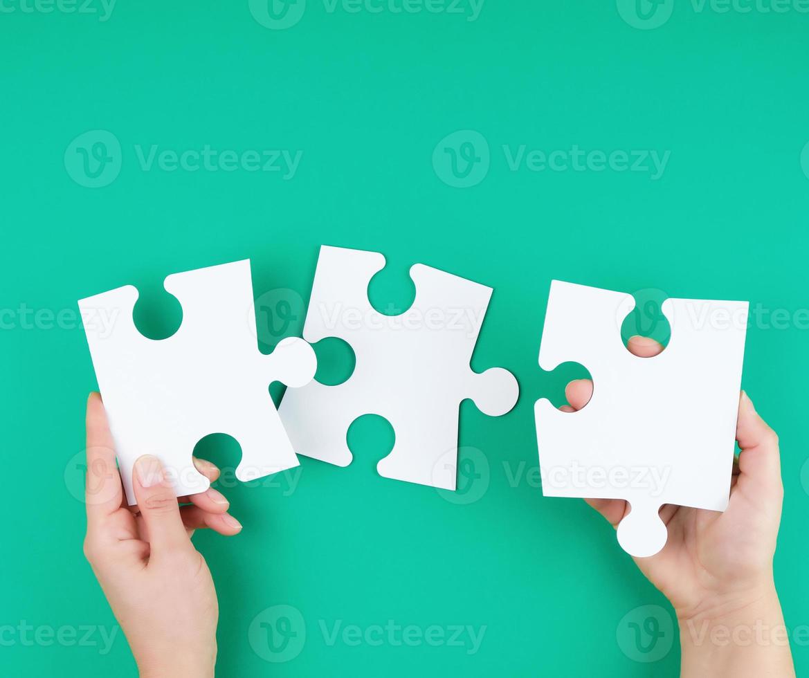 white big puzzles in female hand on green background photo