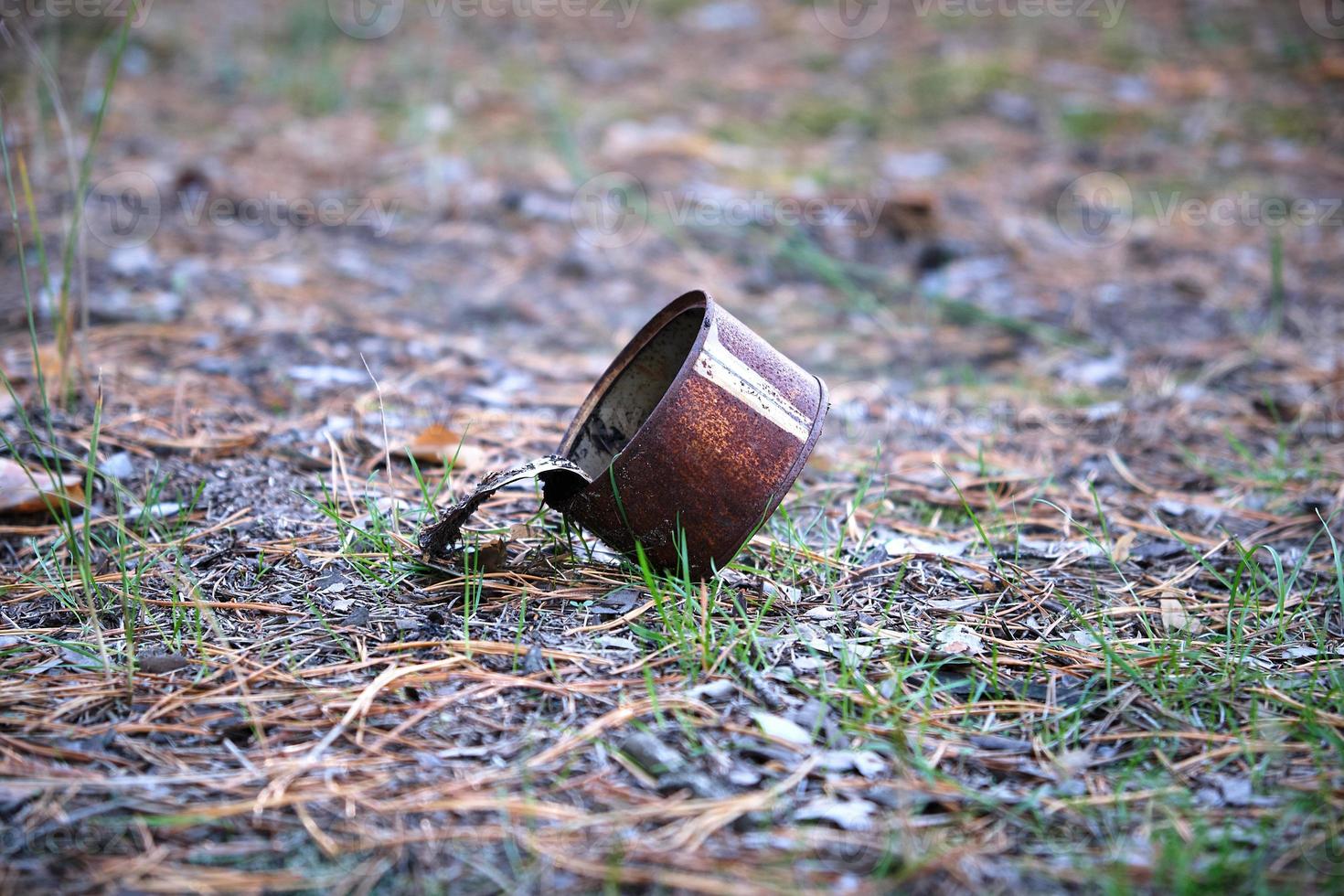 rusty open tin can lying in the middle of the forest photo