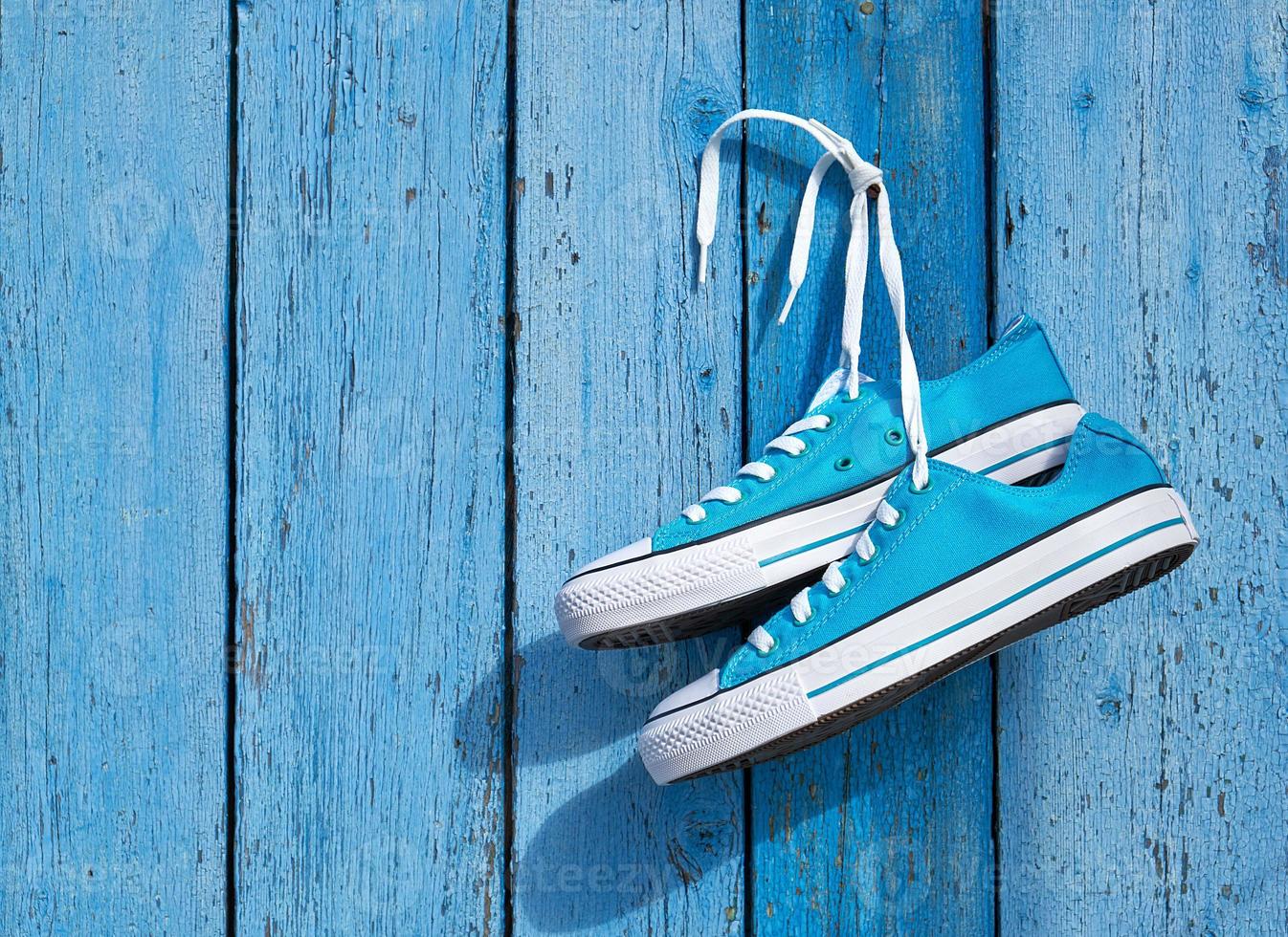 pair of blue textile sneakers hanging on a nail photo