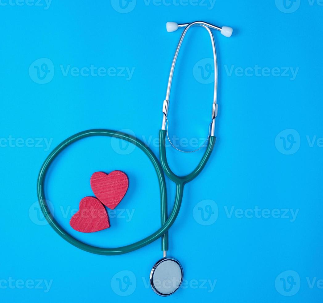 green medical stethoscope and two red wooden hearts photo