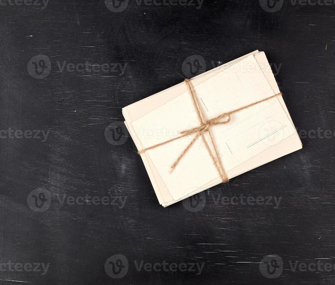 white paper cards tied with a rope on a black wooden background photo