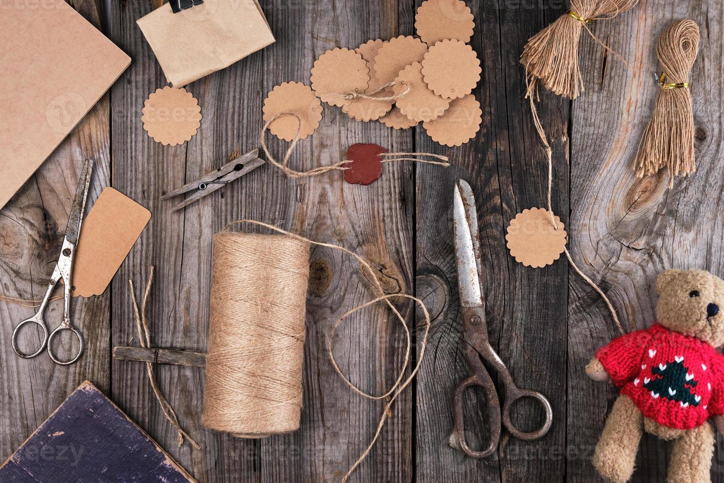 a coil of brown rope, paper tags and old scissors on a gray wooden background photo