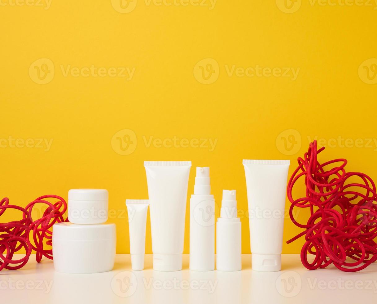 frasco, botella y tubos de plástico blancos vacíos para cosméticos sobre un fondo amarillo. embalaje para crema, gel, suero, publicidad y promoción de productos, maqueta foto