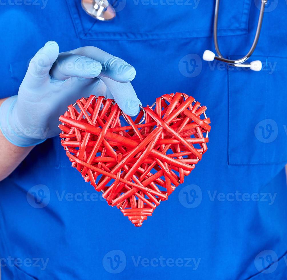 doctor in blue uniform  holds a big red heart photo