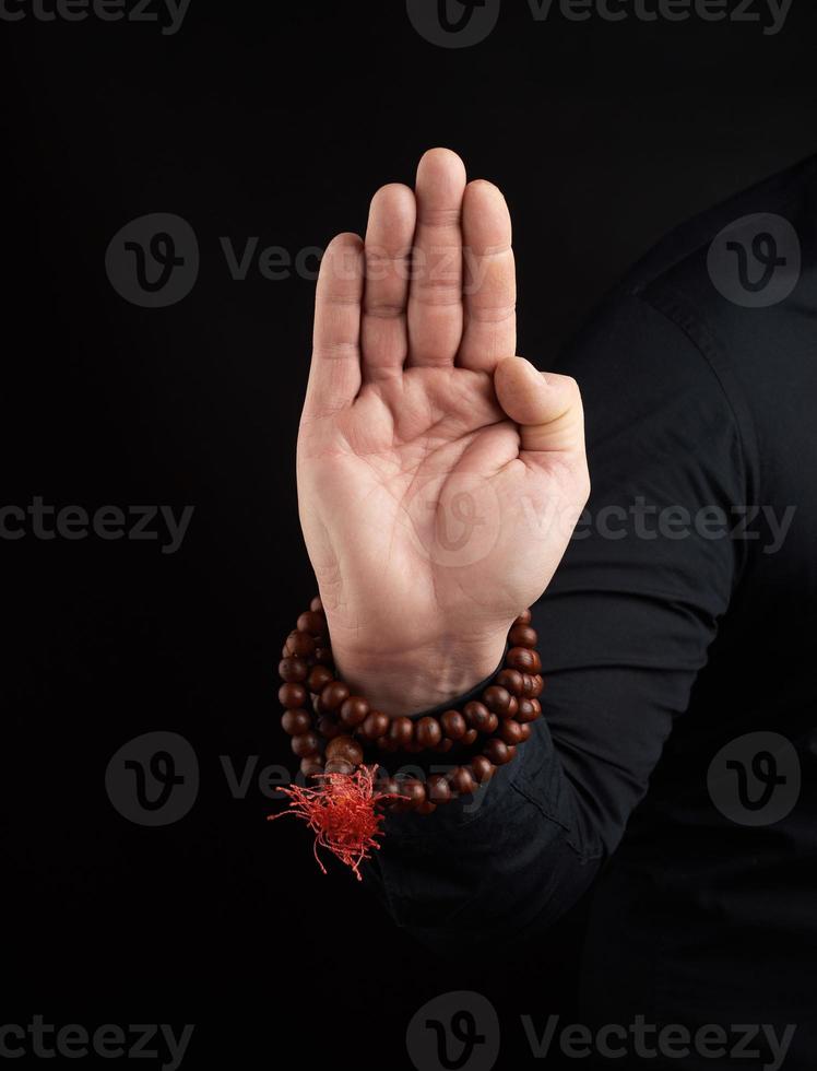 hand of an adult male shows abhayaprada mudra on a dark background, protective gesture photo