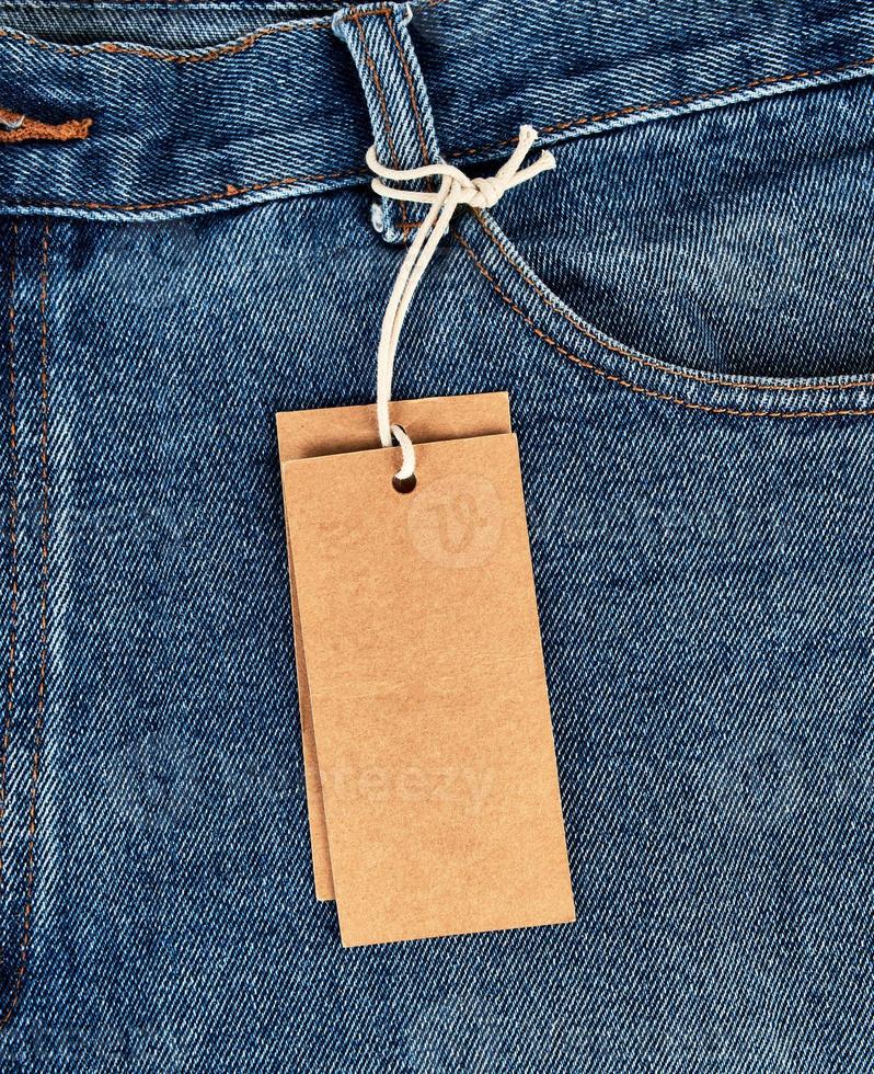 tied on a rope is an empty rectangular brown paper tag on blue jeans photo
