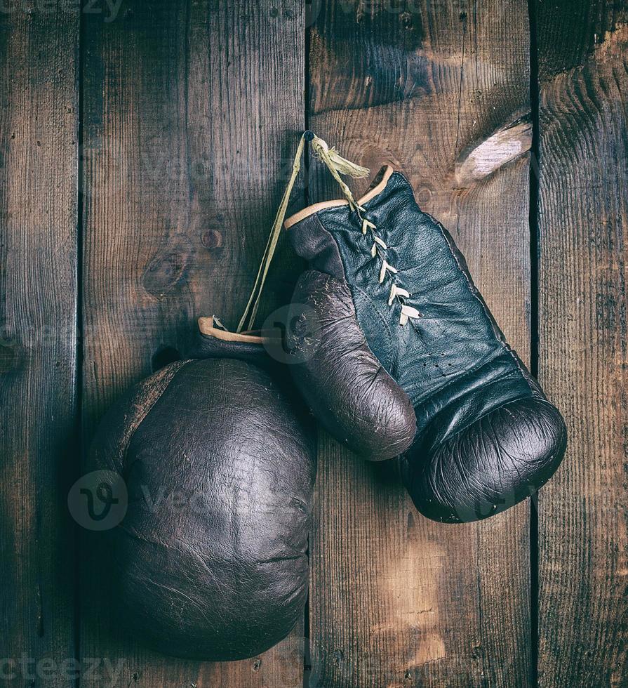 very old shabby leather boxing gloves hanging on a nail photo