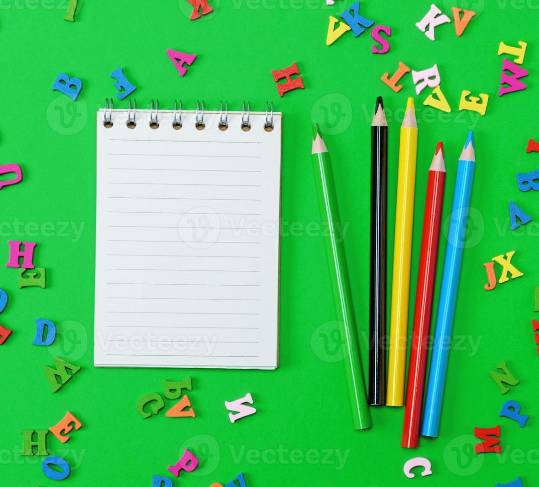 open notebook with blank white sheets in line, colored wooden pencils photo