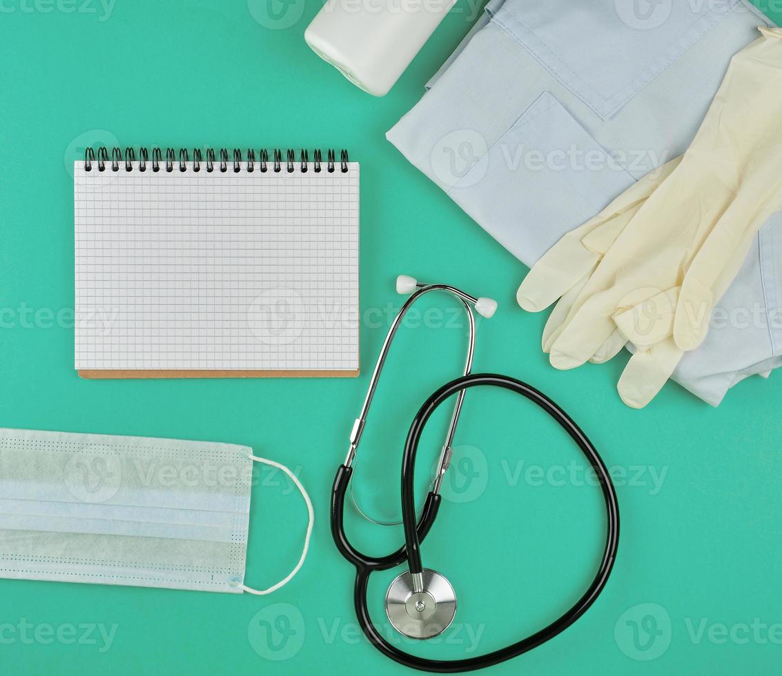 open notebook in line with white sheets, medical mask, stethoscope and bandage photo