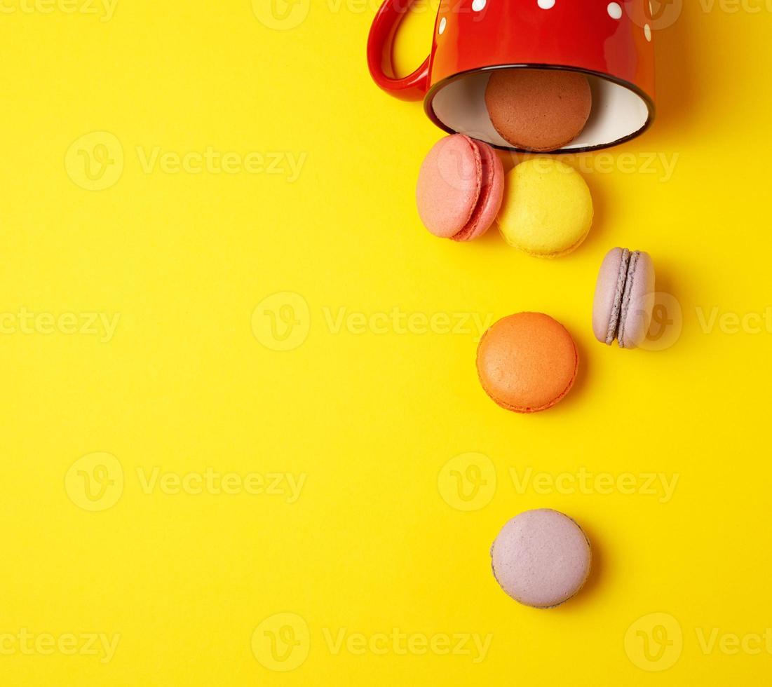 round multicolored macarons falling from a red ceramic cup photo