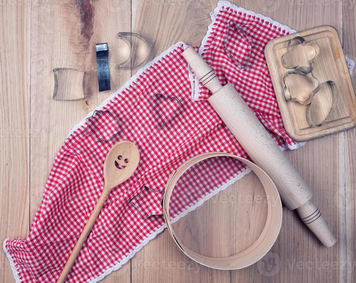 empty round wooden sieve and rolling pin on a red textile kitchen towel photo