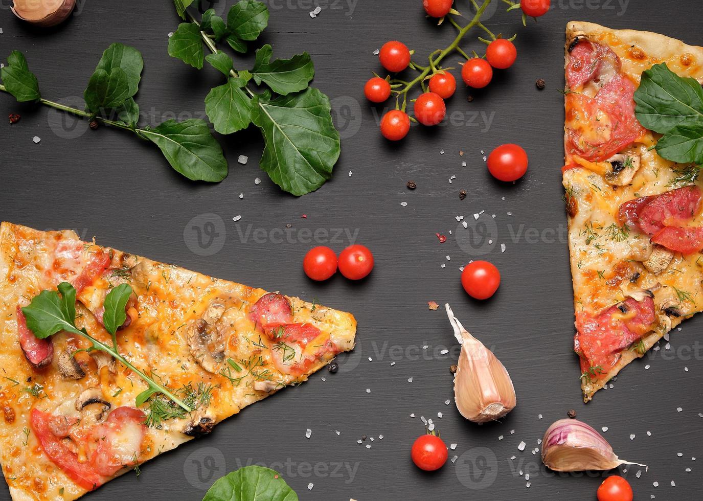 triangular piece of baked pizza with mushrooms, smoked sausages, tomatoes and cheese photo