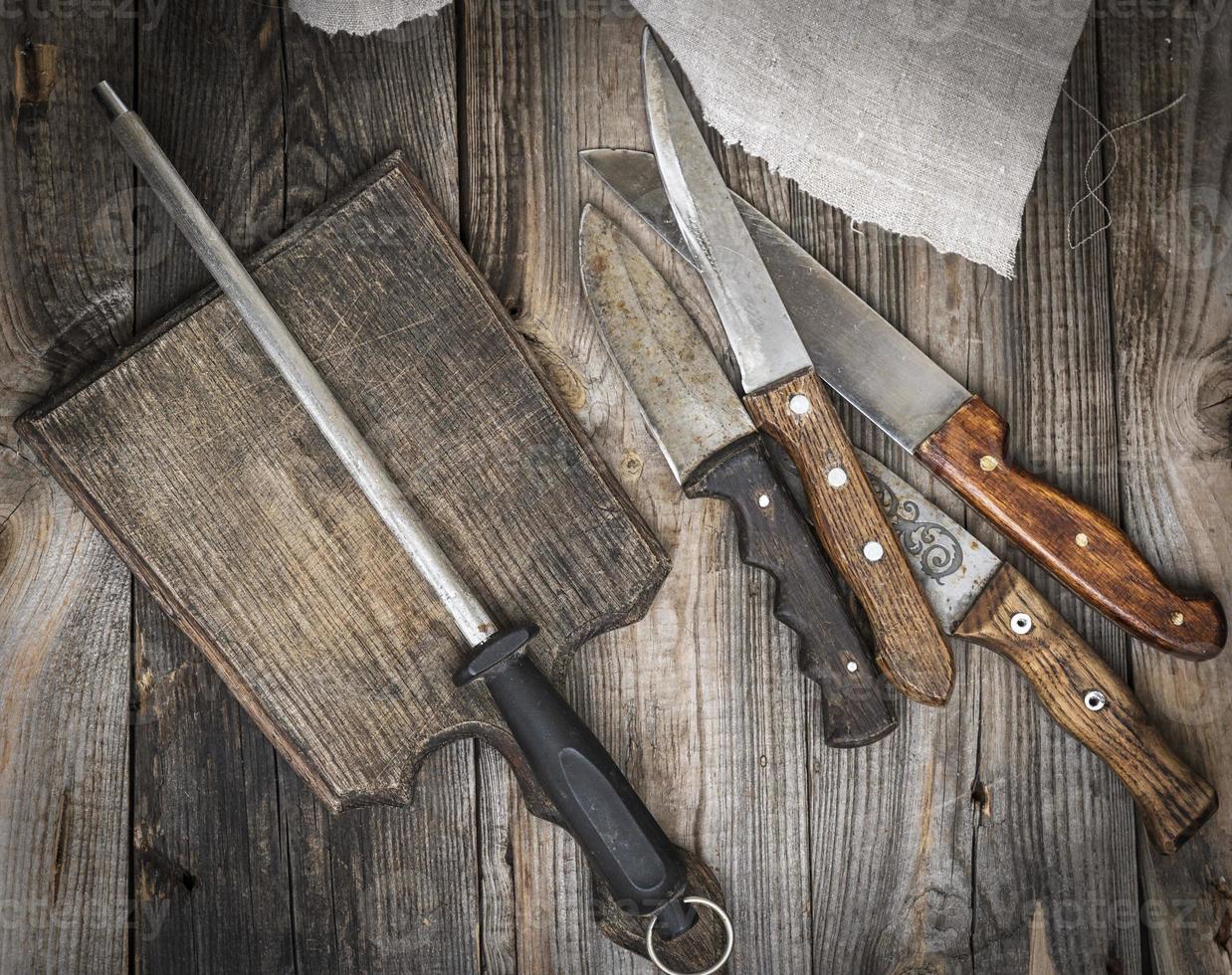 vieja tabla de cortar de madera marrón y cuchillo con afilado en la mesa foto