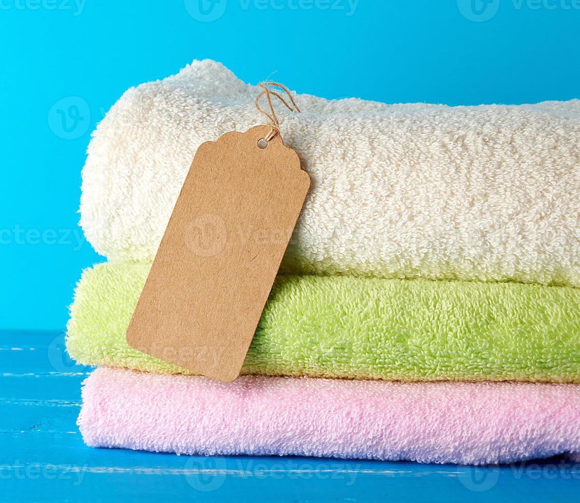 a stack of folded terry colored towels and a brown paper tag on a rope photo