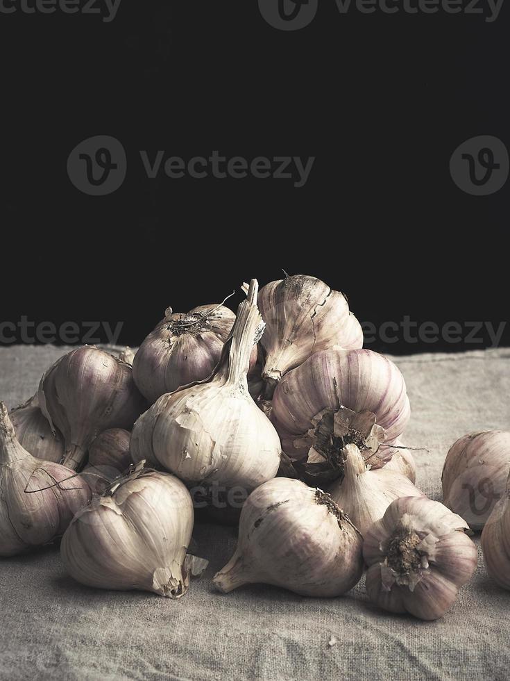 heap of raw unpeeled garlic on a vintage gray linen napkin photo