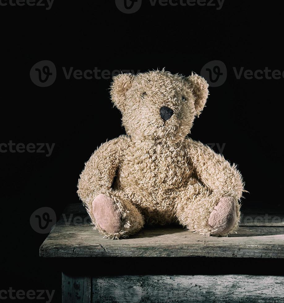 oso de peluche marrón suave sentado sobre un fondo de madera foto