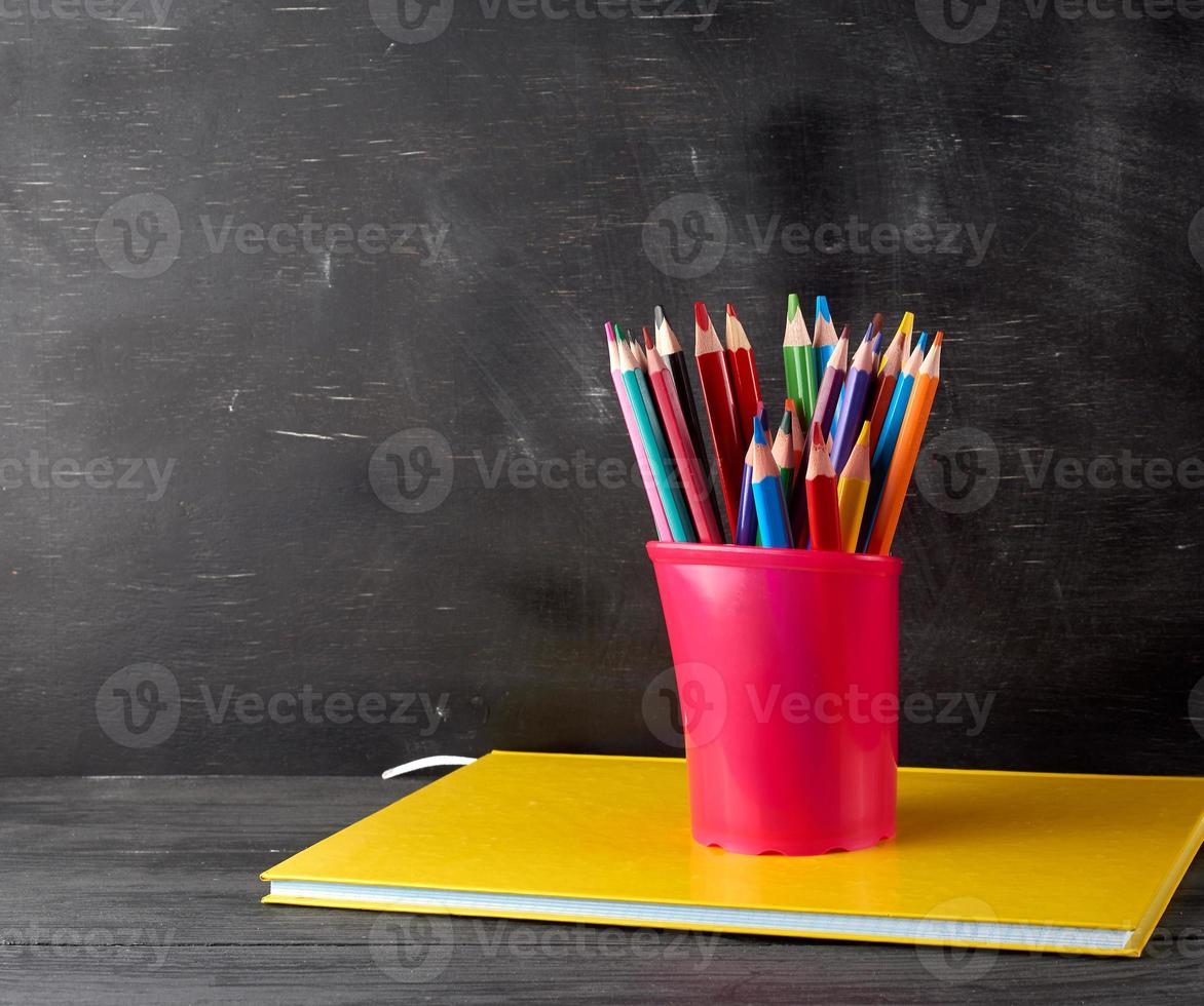 notebook, black stationery glass with multi-colored wooden pencils photo