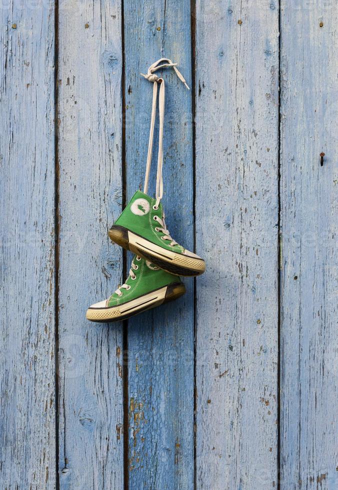 pairs of old textile green classic sneakers hang on a cord photo