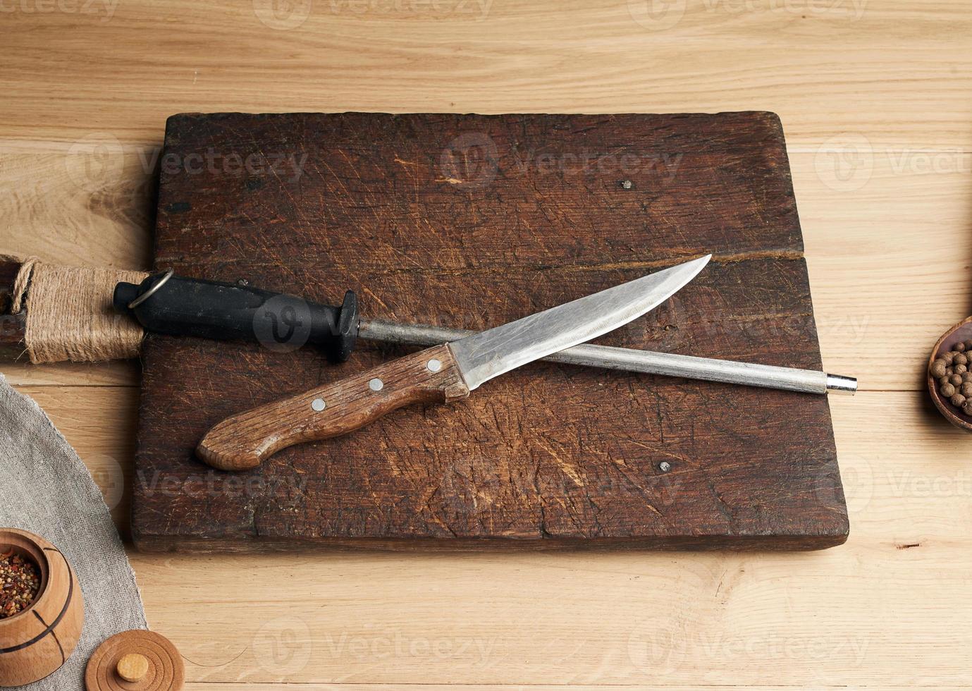 old sharp knife and sharpener with a handle on a wooden background photo
