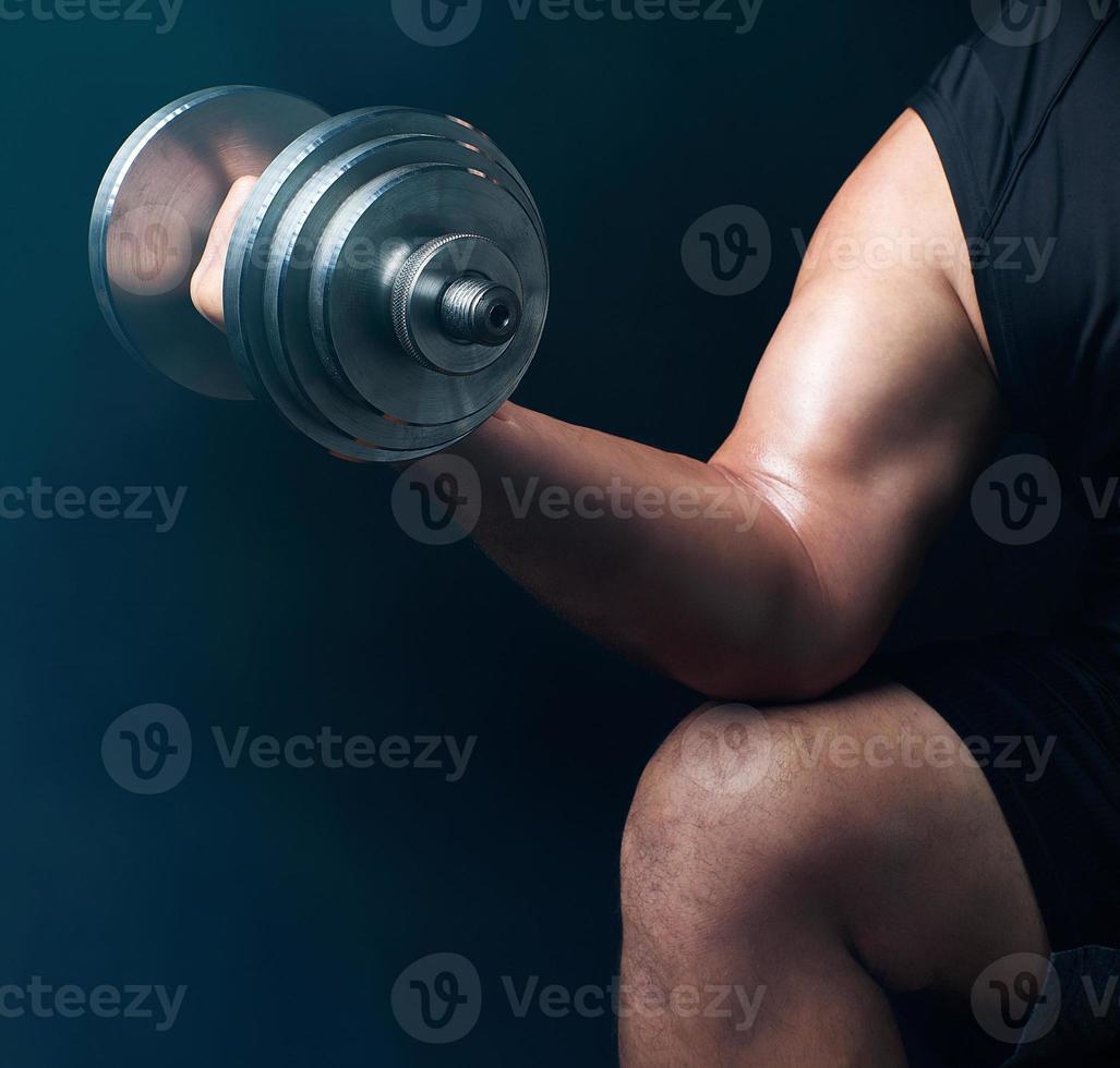 hand of a man with big biceps holds a steel type-setting dumbbell photo