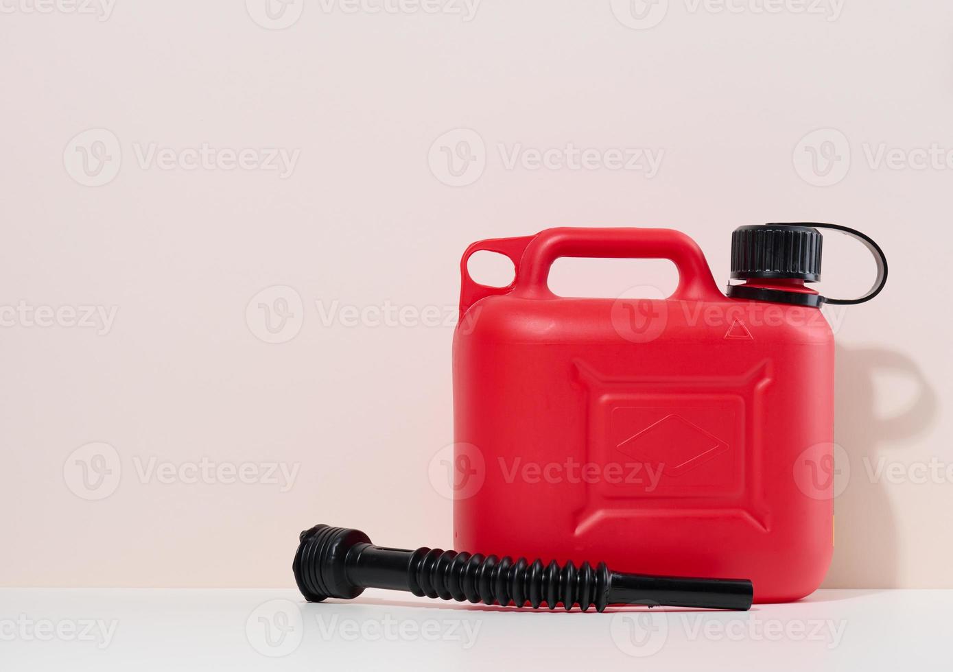 Red plastic canister for liquid fuels and lubricants on a beige background photo