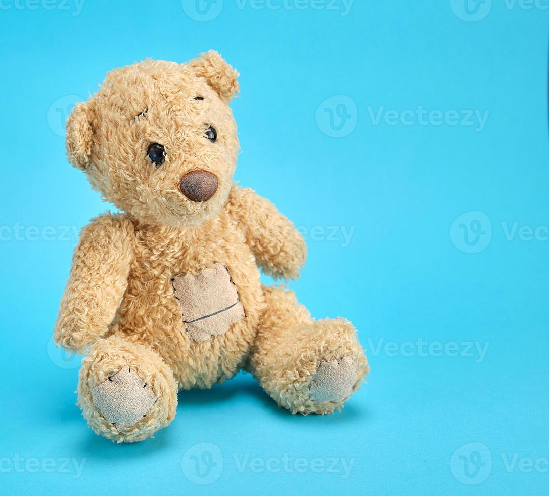 old brown teddy bear on a blue  background photo