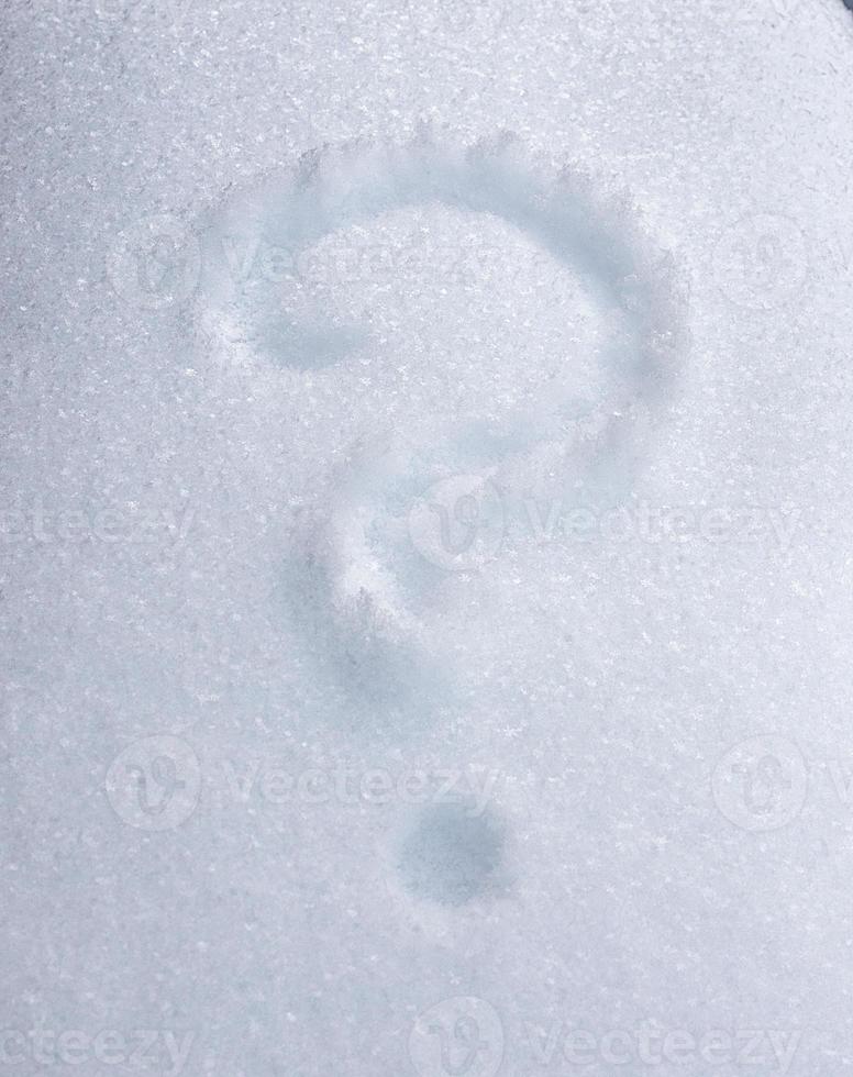 question mark drawn on white snow on a winter day photo