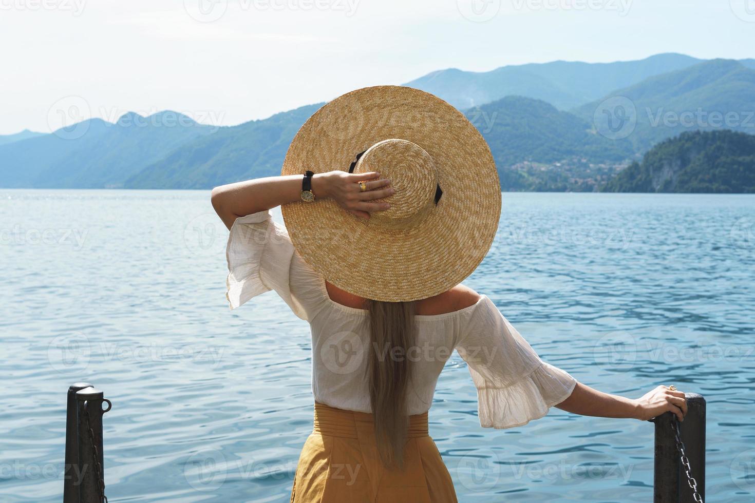 mujer lleva sombrero de paja mirando el hermoso lago foto