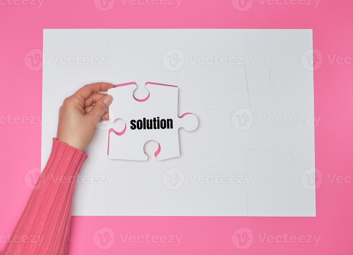 female hand holding white puzzle with the word solution, process of closing the missing element photo