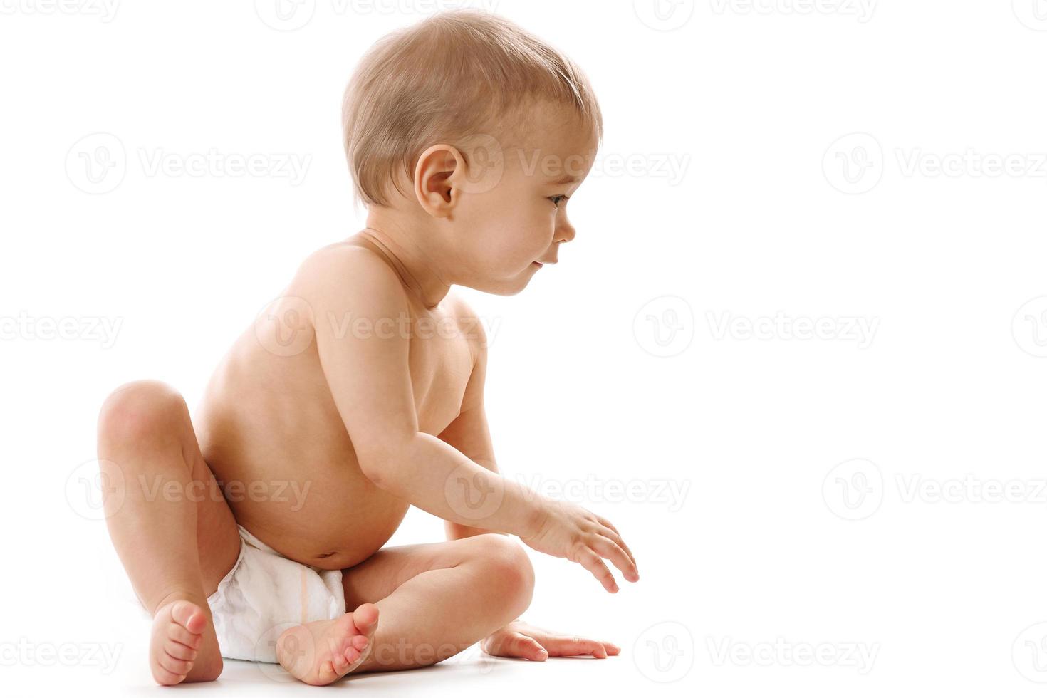 Curious healthy little boy in diaper sitting and looking. photo